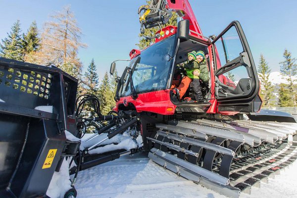 Vater und Sohn schauen von Pistenbully heraus