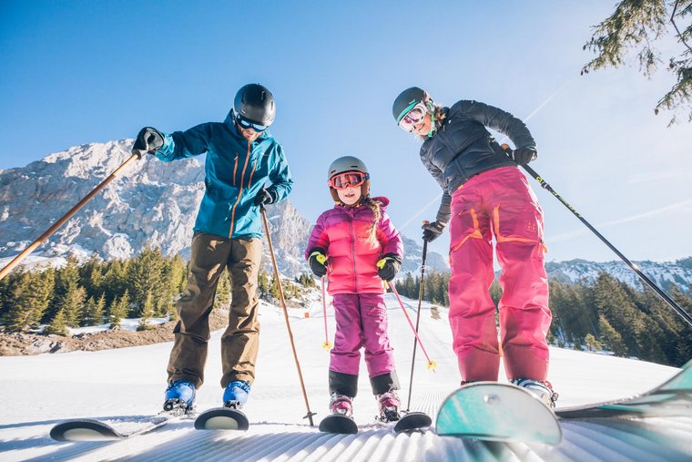 Familie in Skianzug und Skiern steht auf der Piste