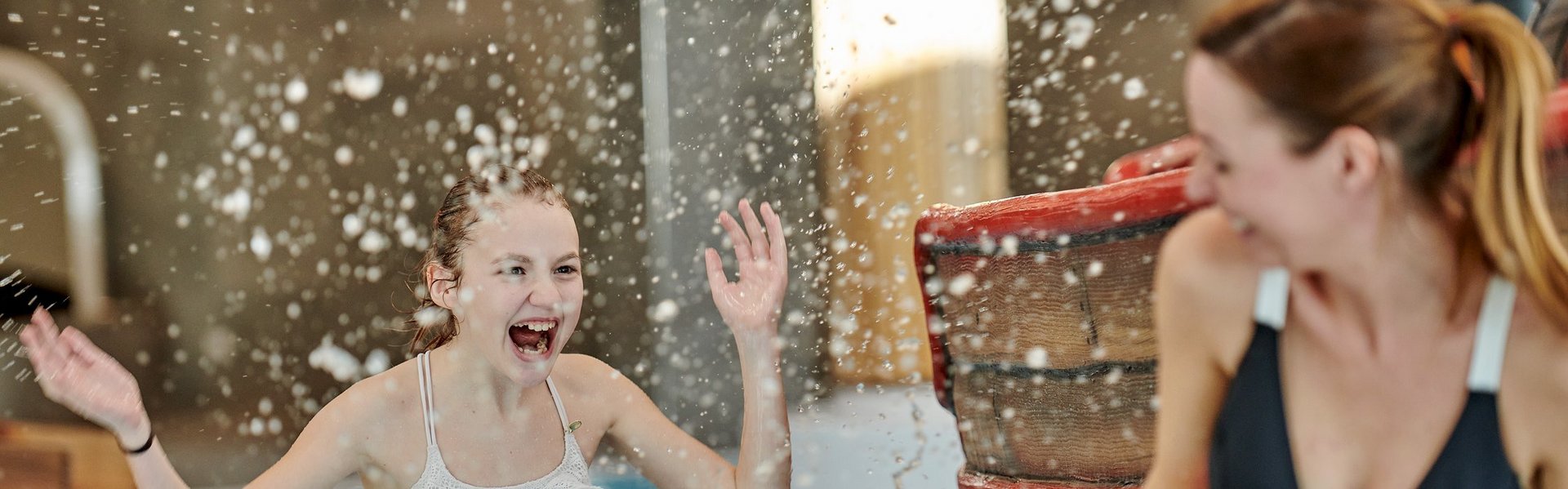 Eine Frau und ein Mädchen lachen und stehen im Indoor-Pool Eine Frau und ein Mädchen lachen und stehen im Indoor-Pool