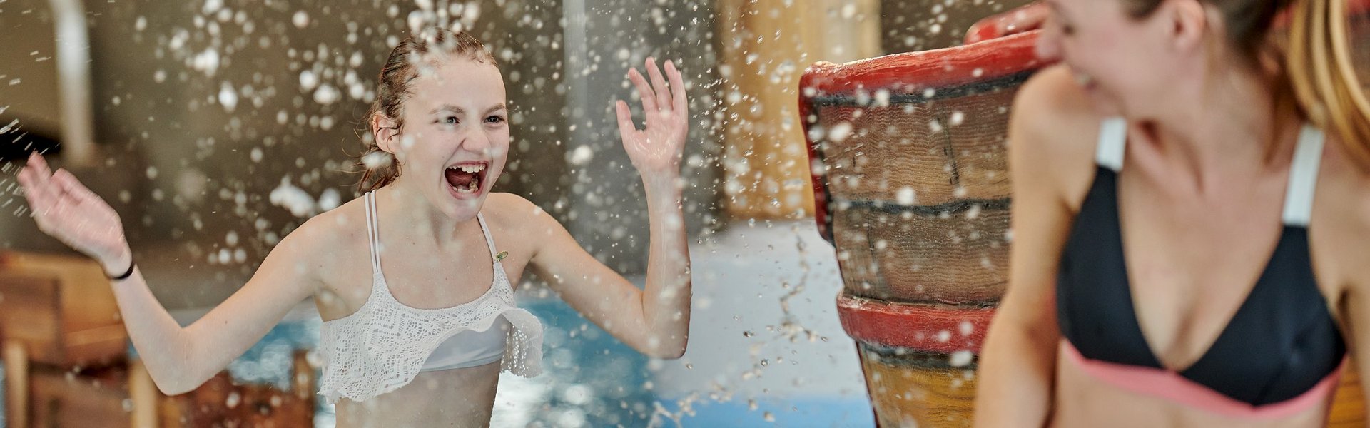 Eine Frau und ein Mädchen lachen und stehen im Indoor-Pool