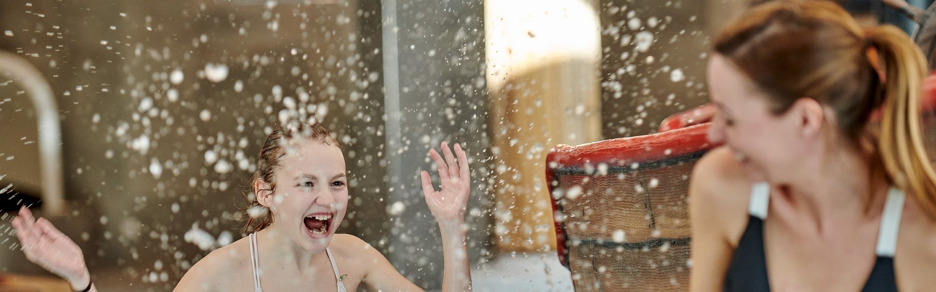 Eine Frau und ein Mädchen lachen und stehen im Indoor-Pool Eine Frau und ein Mädchen lachen und stehen im Indoor-Pool