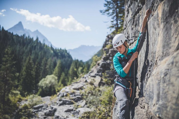 Frau am Klettersteig bei schönem Wetter