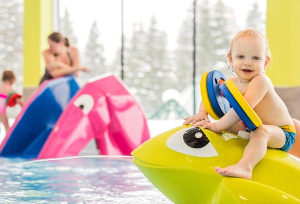 Kleinkind sitzt auf einer Sitzgelegenheit im Kinderpool