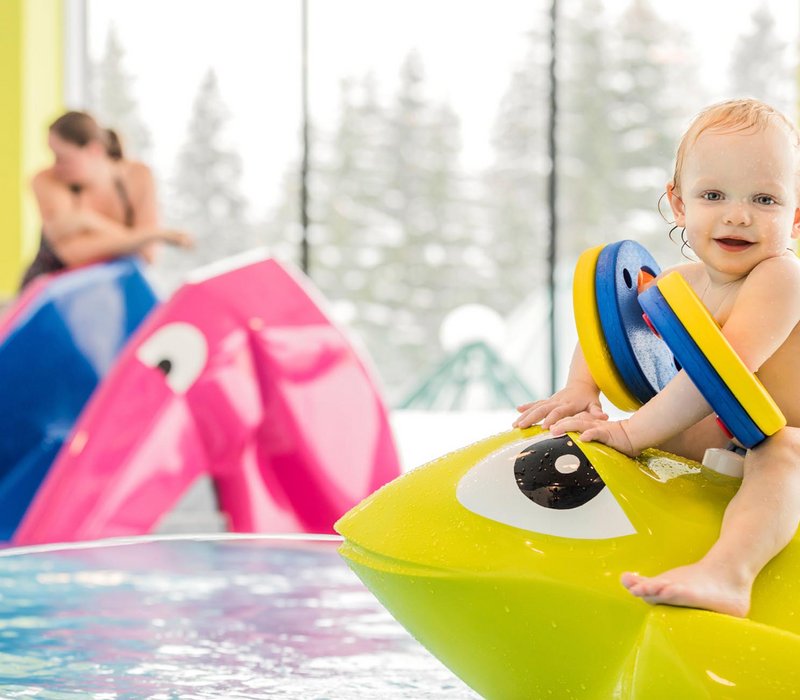 Kleinkind sitzt auf einer Sitzgelegenheit im Kinderpool