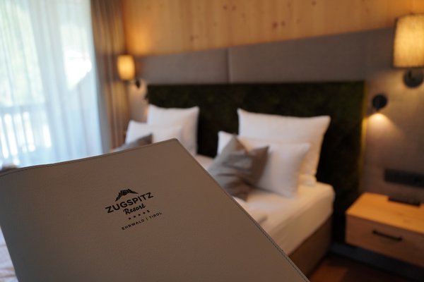 Zimmermappe im Vordergrund und Zimmer im Zugspitz Resort im Hintergrund