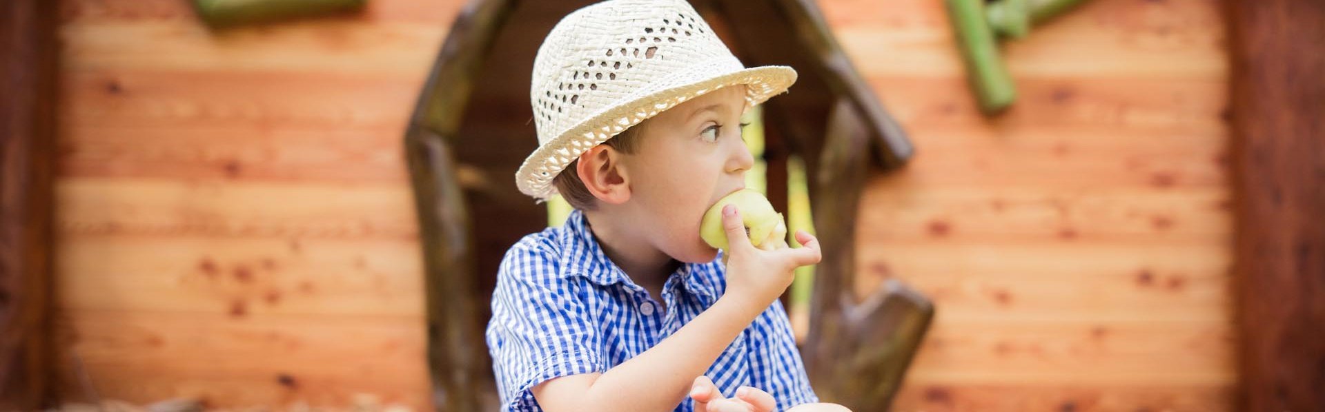 Snacken beim Spielen Kind isst einen Apfel vor dem Kinderspiel-Haus