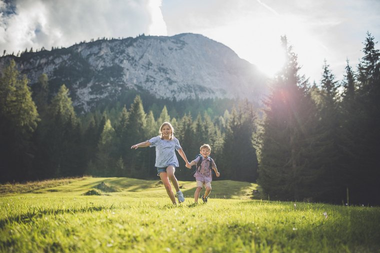 Zwei Kinder laufen durch das grüne Gras