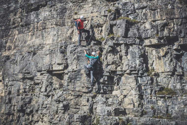 Mann und Frau hängen an Seil auf steiler Felswand