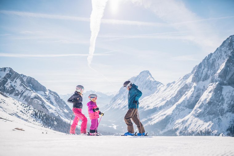 Sonnige Pisten in der Region Familie beim Skifahren auf der Piste