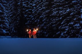 Fackelwanderung in der Region Zwei Personen machen eine Fackelwanderung im Schnee