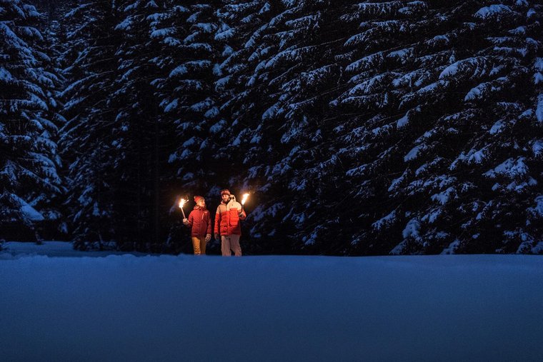 Zwei Personen machen eine Fackelwanderung im Schnee