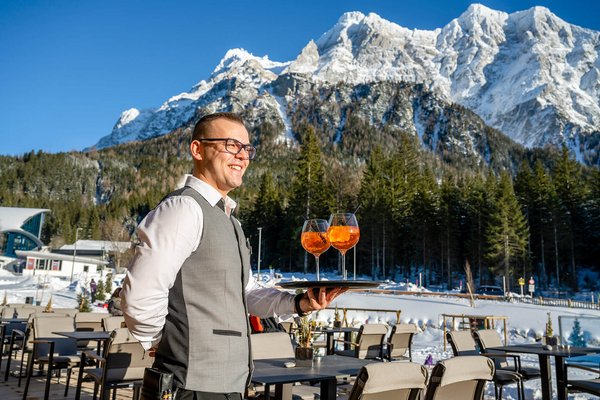 Kellner steht mit Tablett auf der Terrasse mit Zugspitz-Blick