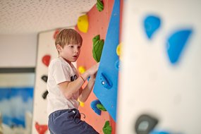 Ein Junge klettert auf der Boulderwand im Zugspitz Resort