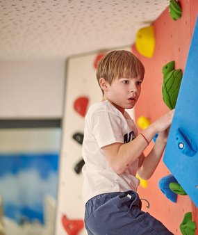 Ein Junge klettert auf der Boulderwand im Zugspitz Resort