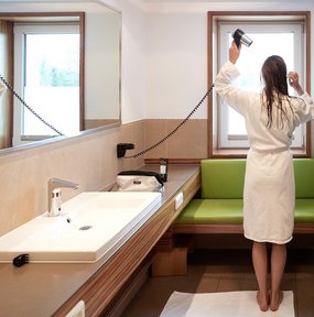 Deluxe Badehaus Frau föhnt ihre Haare im Badehaus im Zugspitz Resort