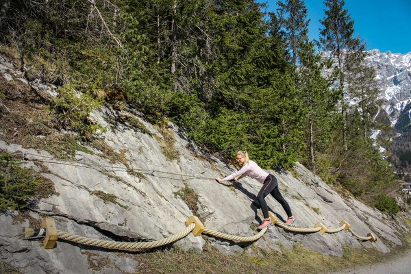 Frau beim Klettern auf einer niedrigen Felswand