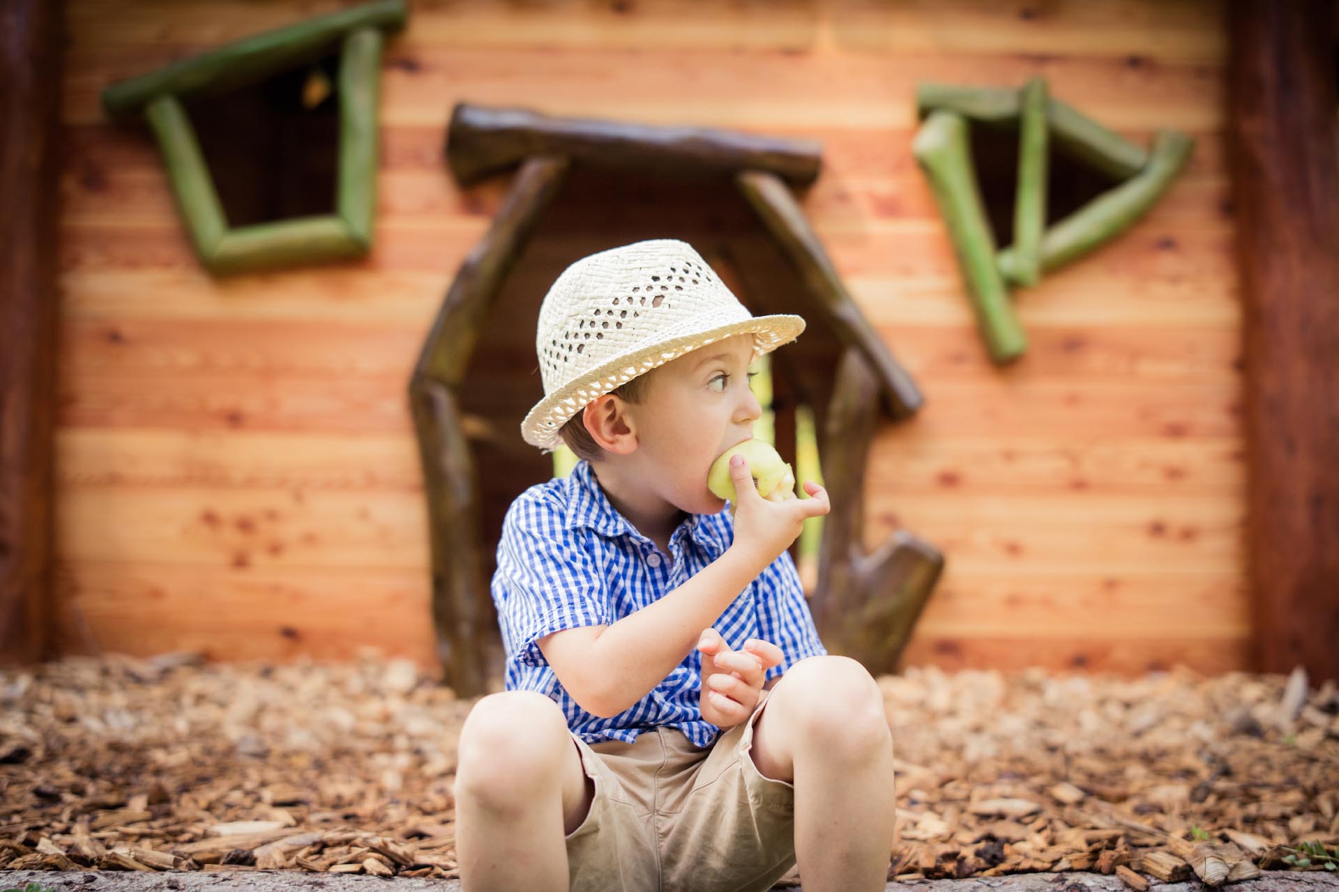 Kind isst einen Apfel vor dem Kinderspiel-Haus 